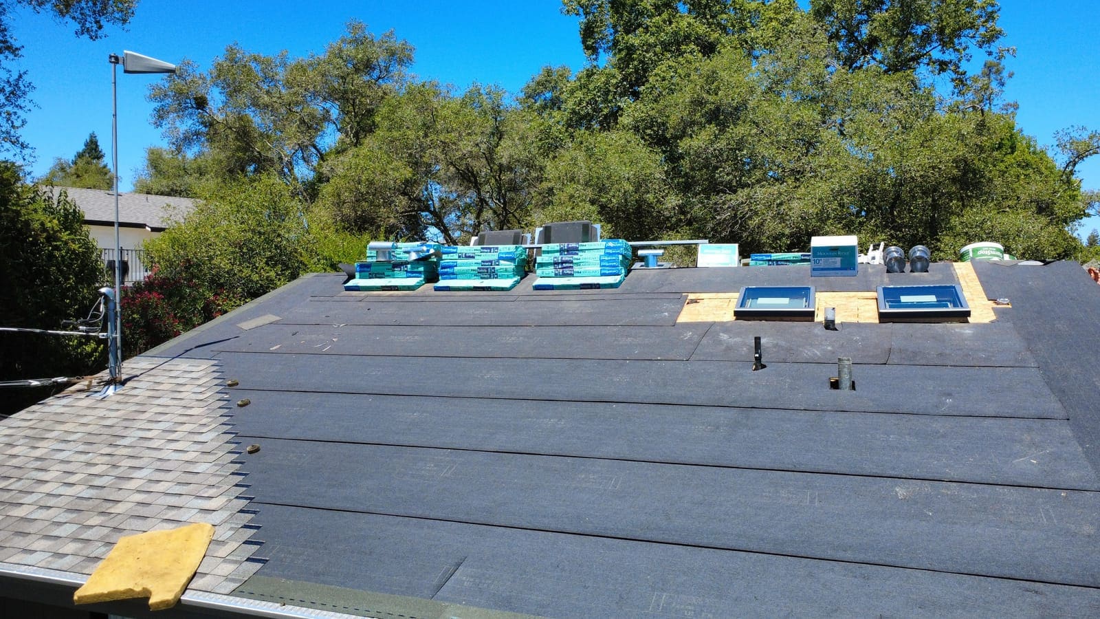 Roof fully dried in with underlayment and materials staged along the ridge