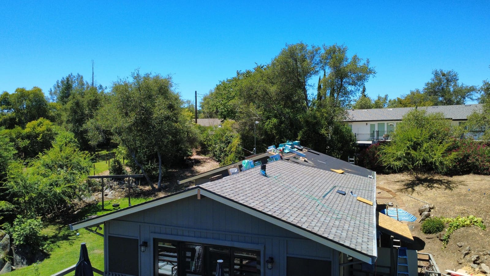 New shingles being installed across the roof with materials staged at the ridge