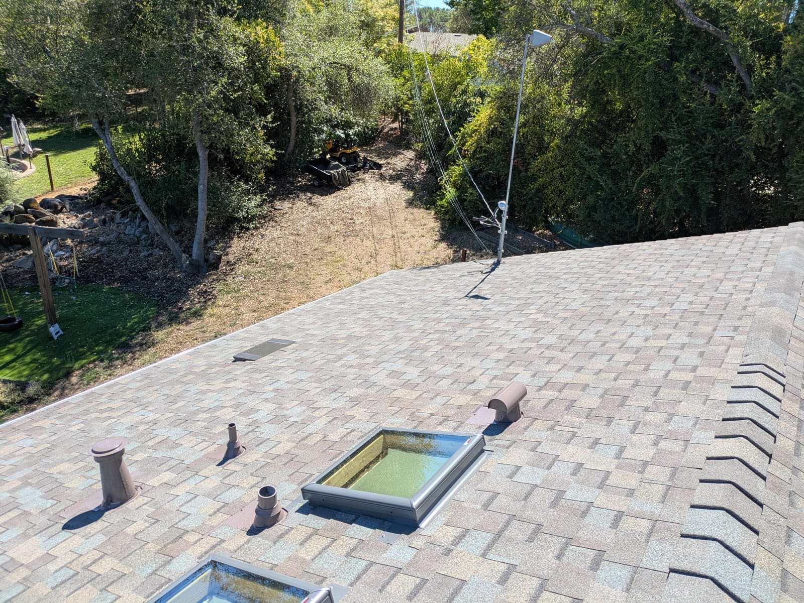 Finished shingle roof with new skylight, vents, and pipe flashings installed
