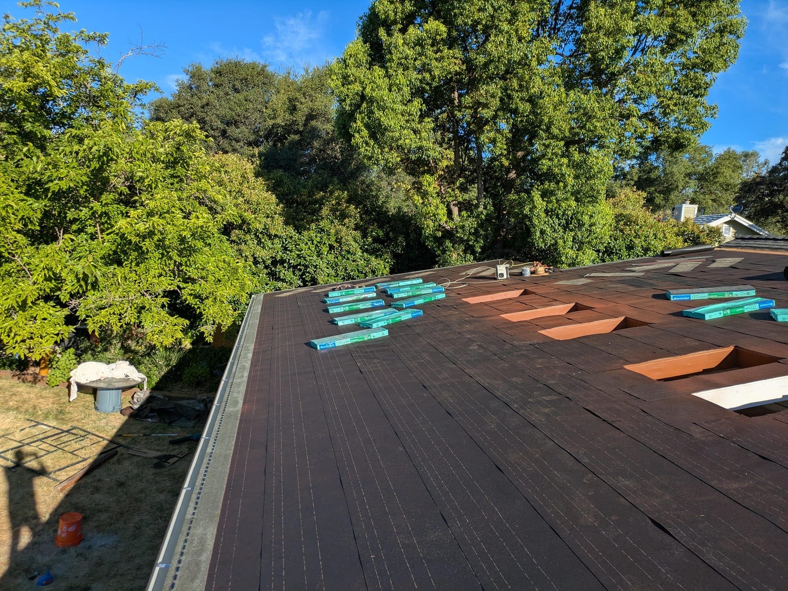 Roof deck covered in underlayment with skylight curbs framed and shingle bundles arriving